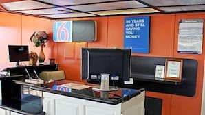 A reception desk with a sign that reads "50 YEARS AND STILL SAVING YOU MONEY." - Motel 6 Sallisaw, OK (Sallisaw)
