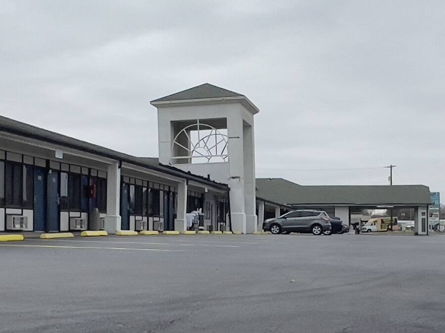 A motel with a large '6' sign, a clock tower, and a parking lot.