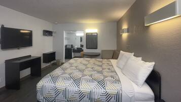 A hotel room with a large bed, a TV, a desk, and a mirror.