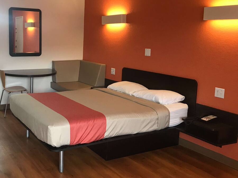 A hotel room with a bed, a desk, a chair, and a small table.