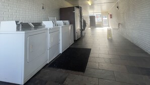 A laundry area with white appliances, a black mat, and a tiled floor. - Motel 6 Sallisaw, OK (Sallisaw)