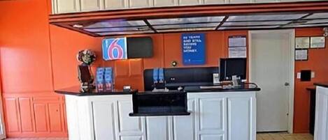 A reception area with a counter, a blue sign with text, and a door.
