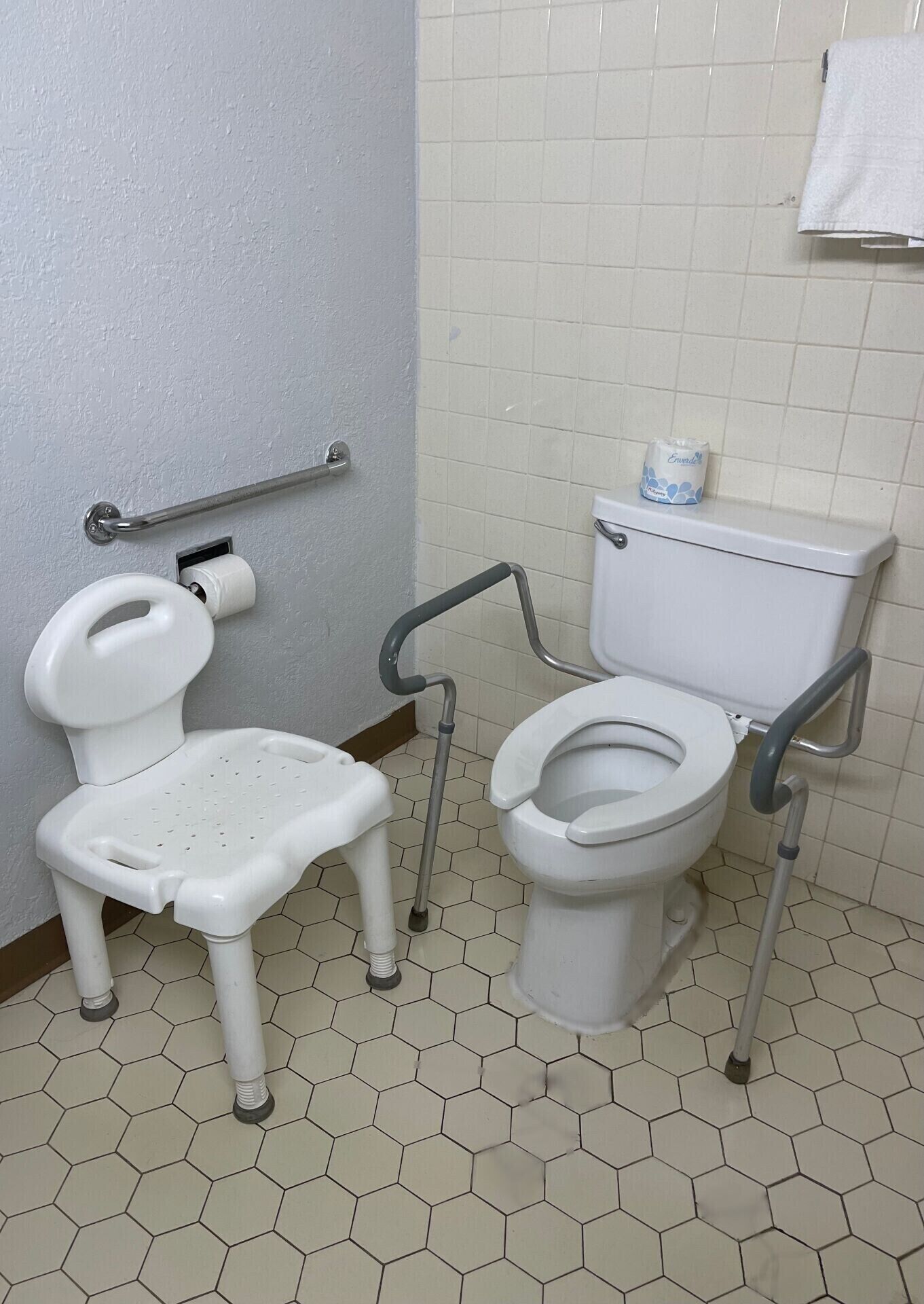 Une salle de bain accessible aux personnes en fauteuil roulant, équipée de toilettes et d’un bidet, d’une barre d’appui et d’un porte-rouleau de papier toilette.