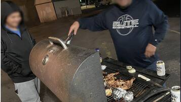 A person grilling meat on an outdoor barbecue.