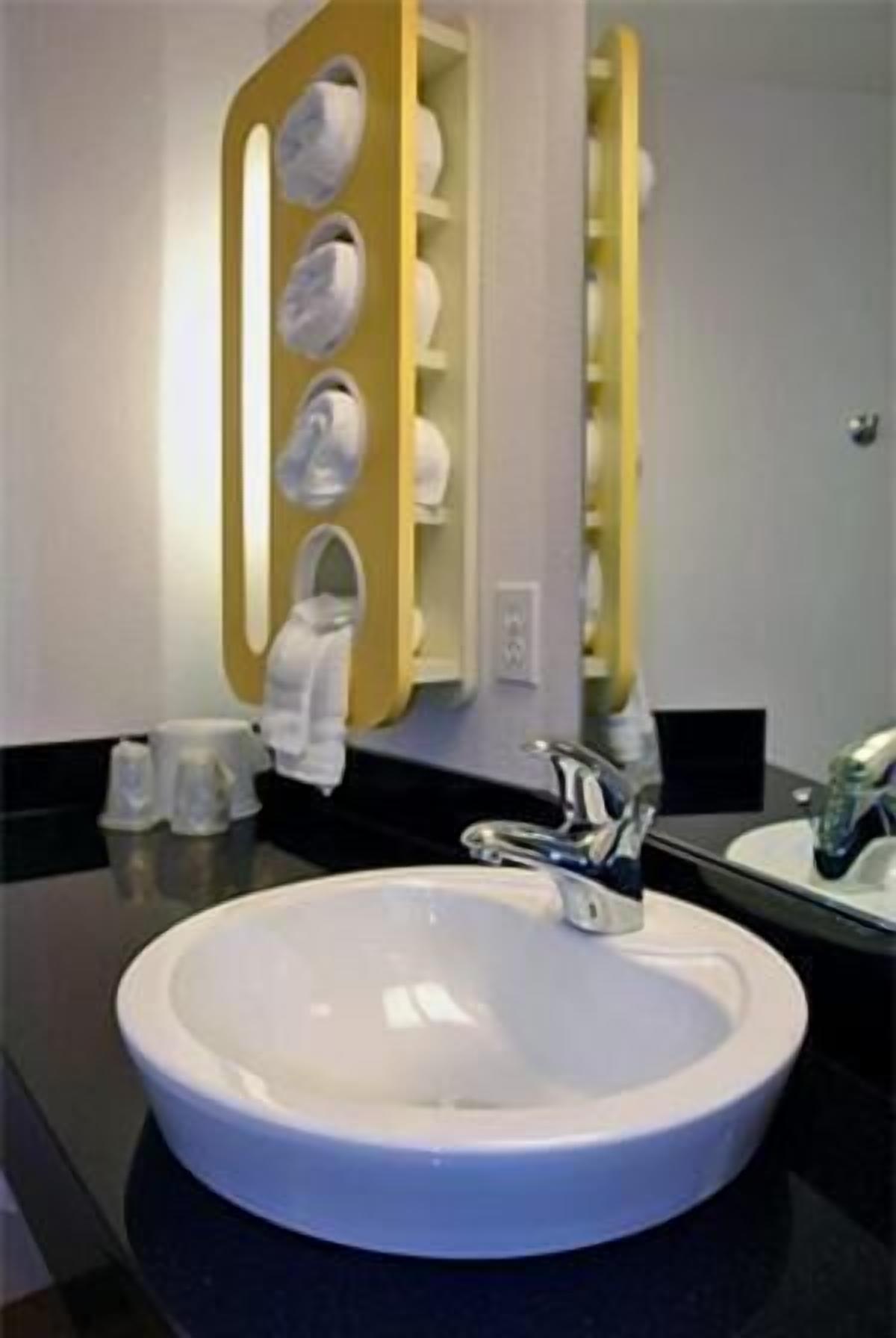 A bathroom with a white sink, a mirror, and a towel rack.