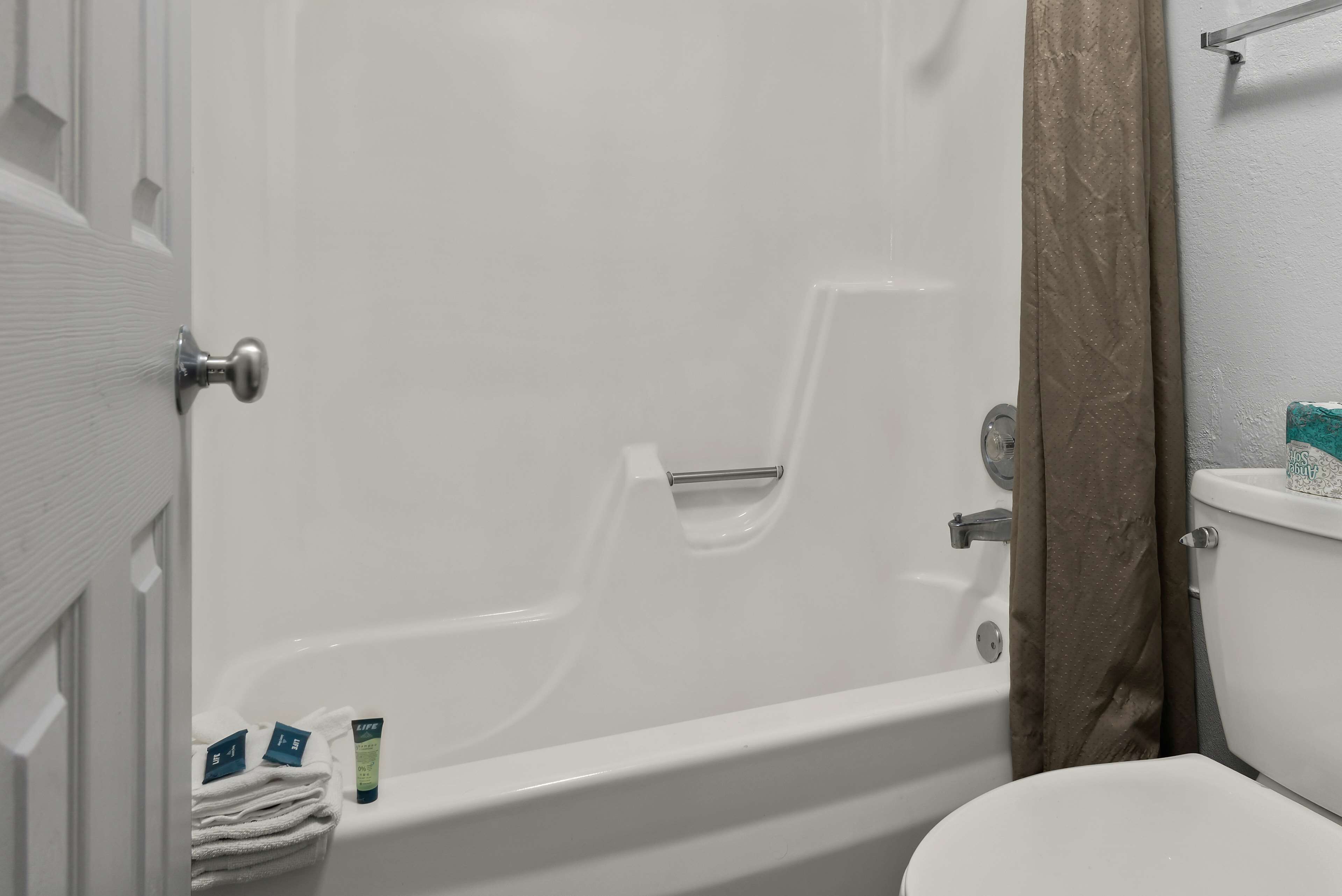 Et badeværelse med badekar, toilet og et håndklædestativ.