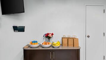 Zona de recepción con mostrador que exhibe cuencos de fruta, un florero y bolsas de papel.