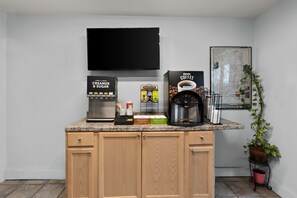 A kitchen with a coffee machine, a TV mounted above the counter, and a map on the wall. - Americas Best Value Inn Bangor (Bangor)