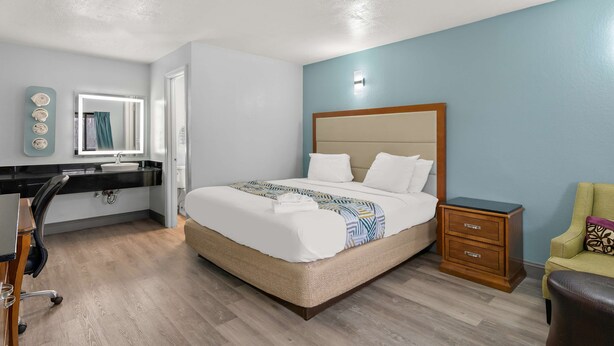 Ein ordentlich eingerichtetes Schlafzimmer mit Bett, Nachttisch, Stuhl, Schreibtisch und Spiegel.