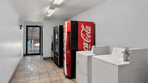 Ein Waschraum mit einem Coca-Cola-Automaten, einer Waschmaschine und einem Trockner.