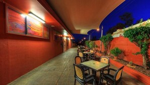 A corridor with tables and chairs, a red wall, and a blue sky. - Best Western Halls Creek Motel (Halls Creek)