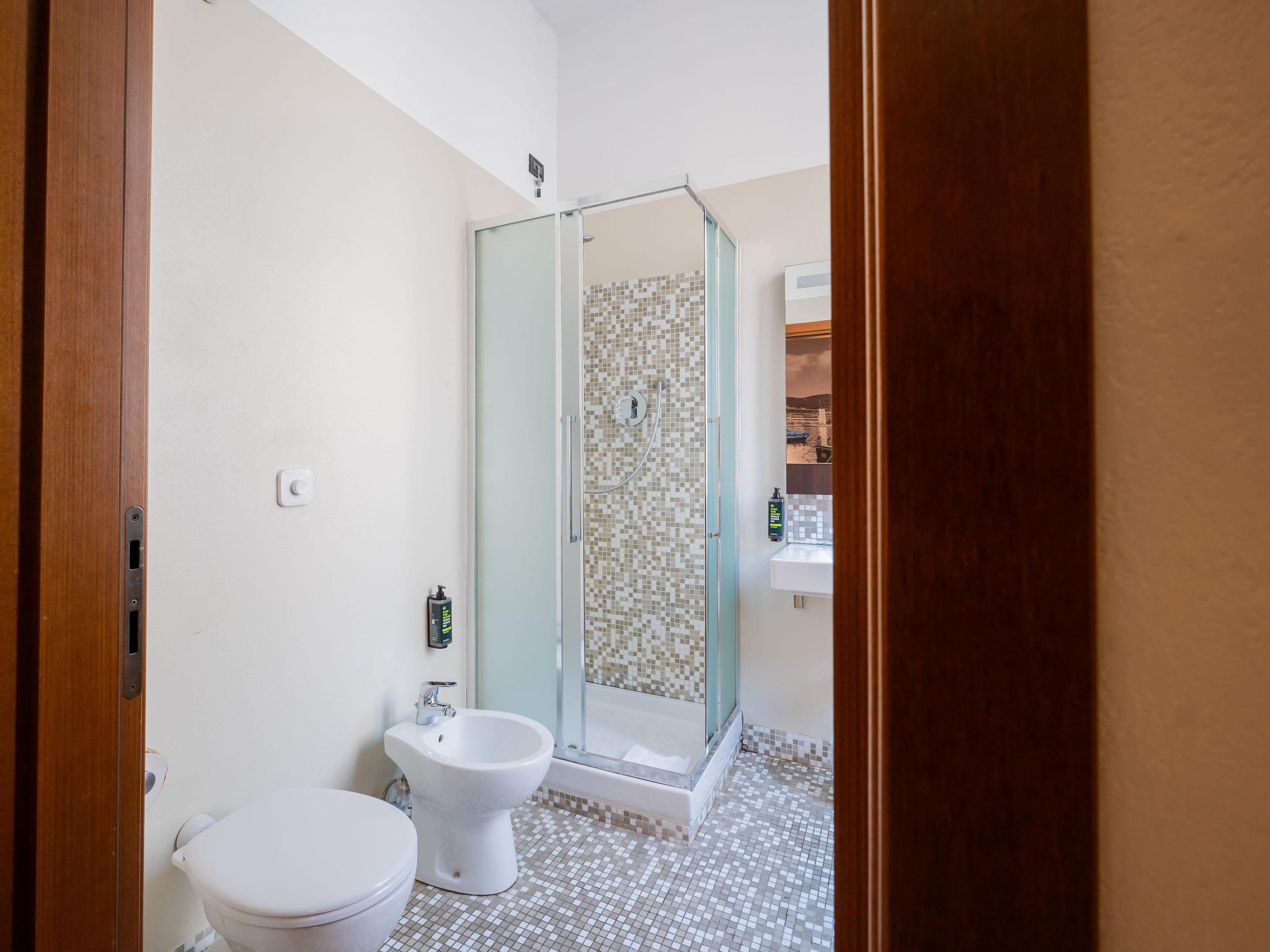 A bathroom with a toilet, bidet, and a glass-enclosed shower.