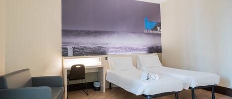 A hotel room with a bed, a desk, and a chair.