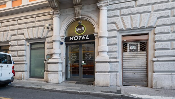 A hotel entrance with a sign reading "B&B HOTELS" and a closed shutter door. - B&B Hotel Trieste (Trieste)