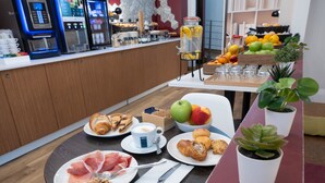 A breakfast setting with croissants, pastries, fruits, and a coffee machine. - B&B Hotel Trieste (Trieste)