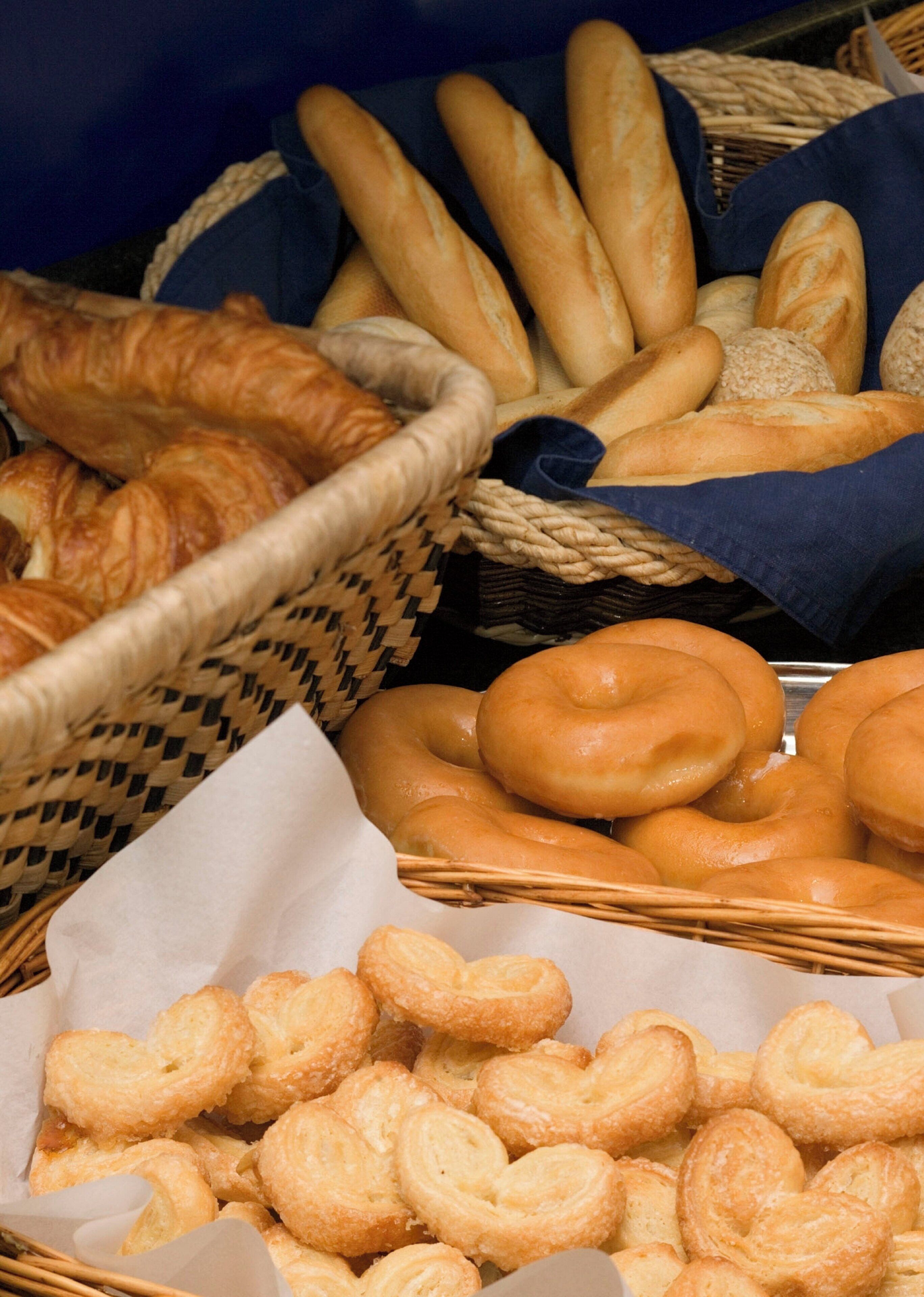 Diverse gebakken producten, waaronder brood, croissants en gebakjes, gepresenteerd in manden.