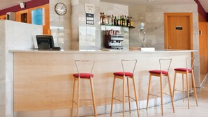 Uma área de bar com balcão, banquetas, um relógio e um aviso proibindo fumar.