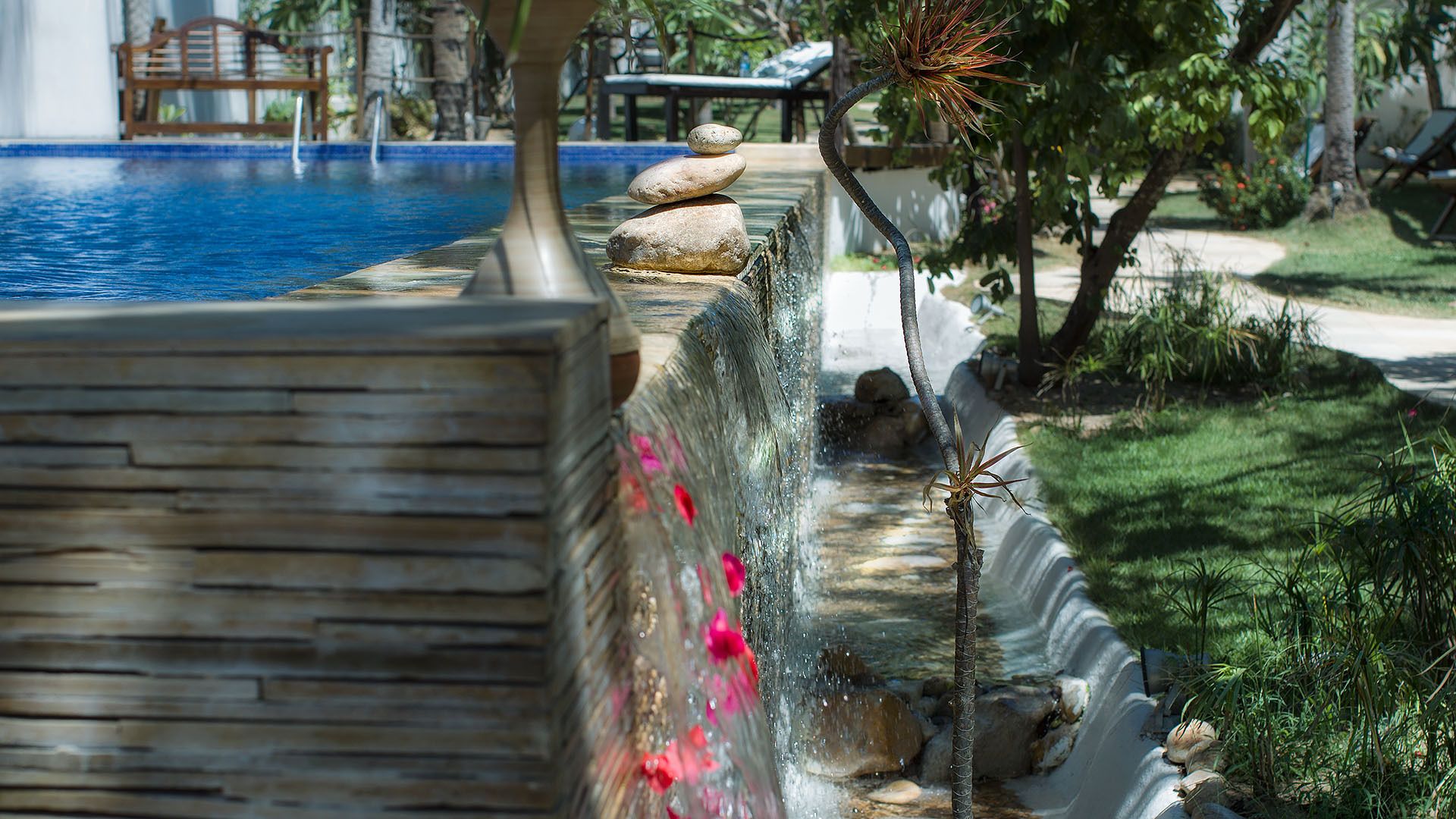 Una piscina con un muro de piedra y una pequeña cascada.