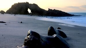 A beach with large rocks and a prominent rock formation in the background. - My Blue Hotel (Jijoca de Jericoacoara)