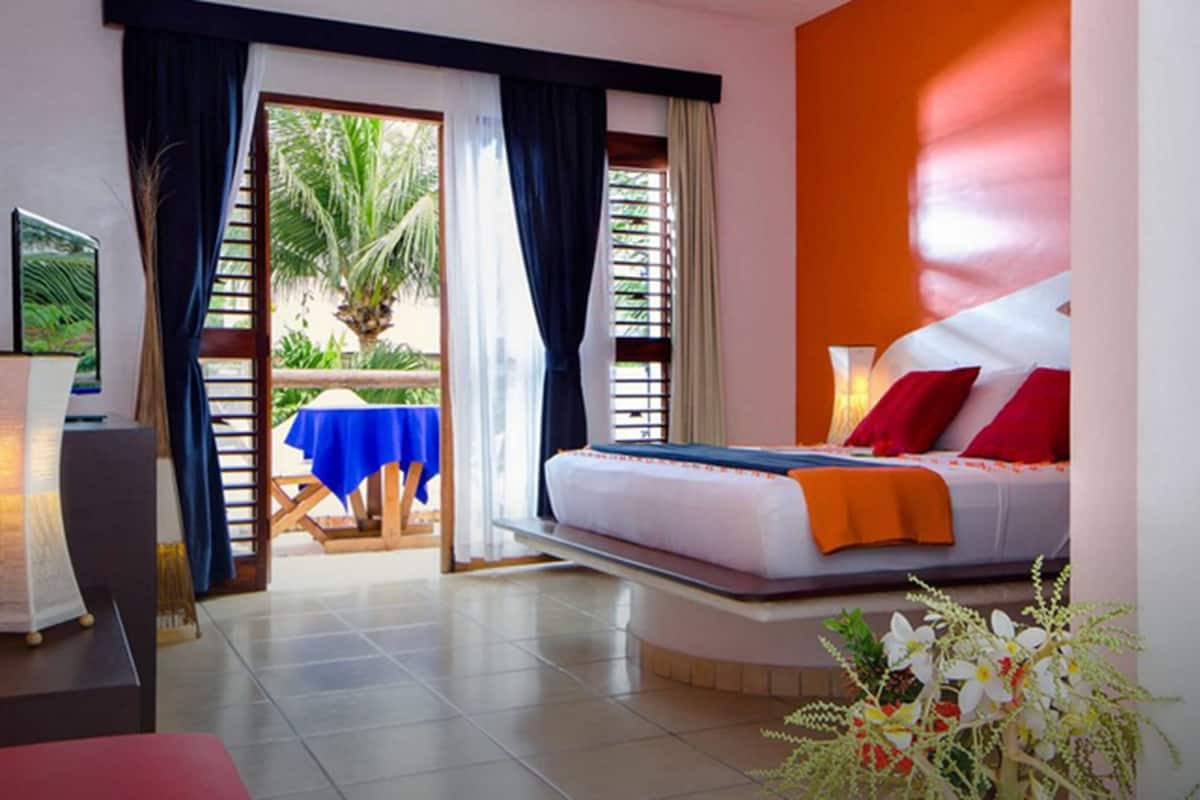 A modern hotel room with a bed, a desk, and a view of the outdoors.