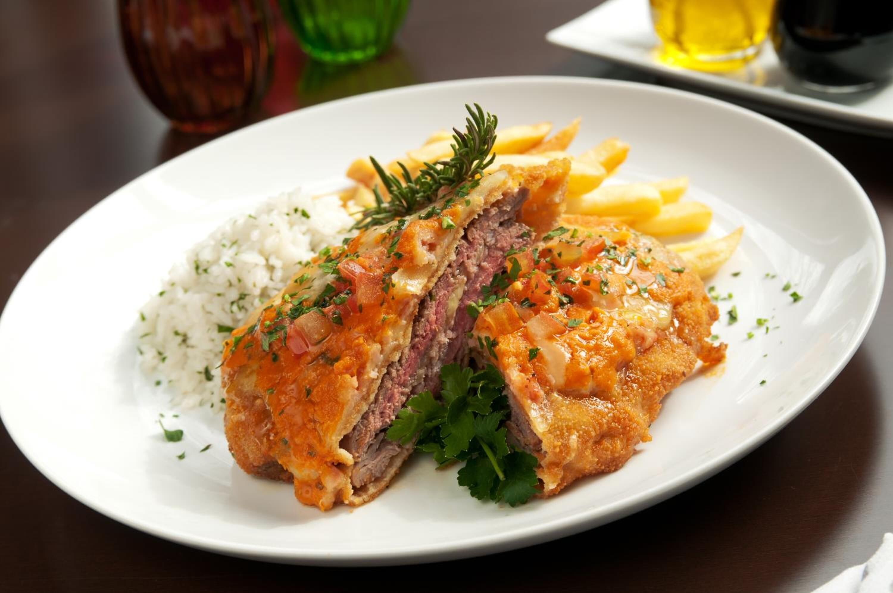 Un plato de comida con un guiso de carne, arroz y papas fritas.