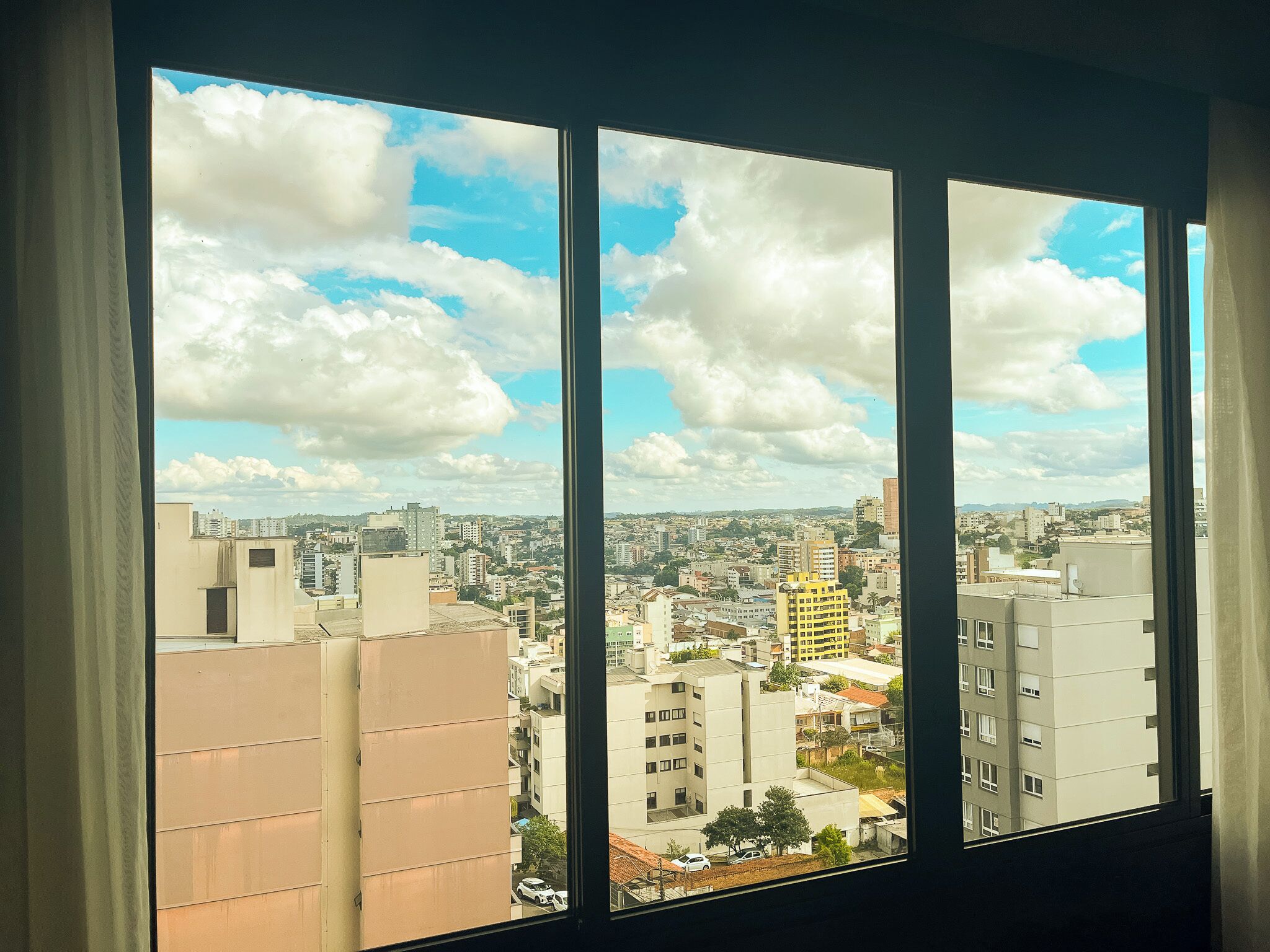 Panorama urbano a través de una ventana, mostrando edificios y un cielo despejado.