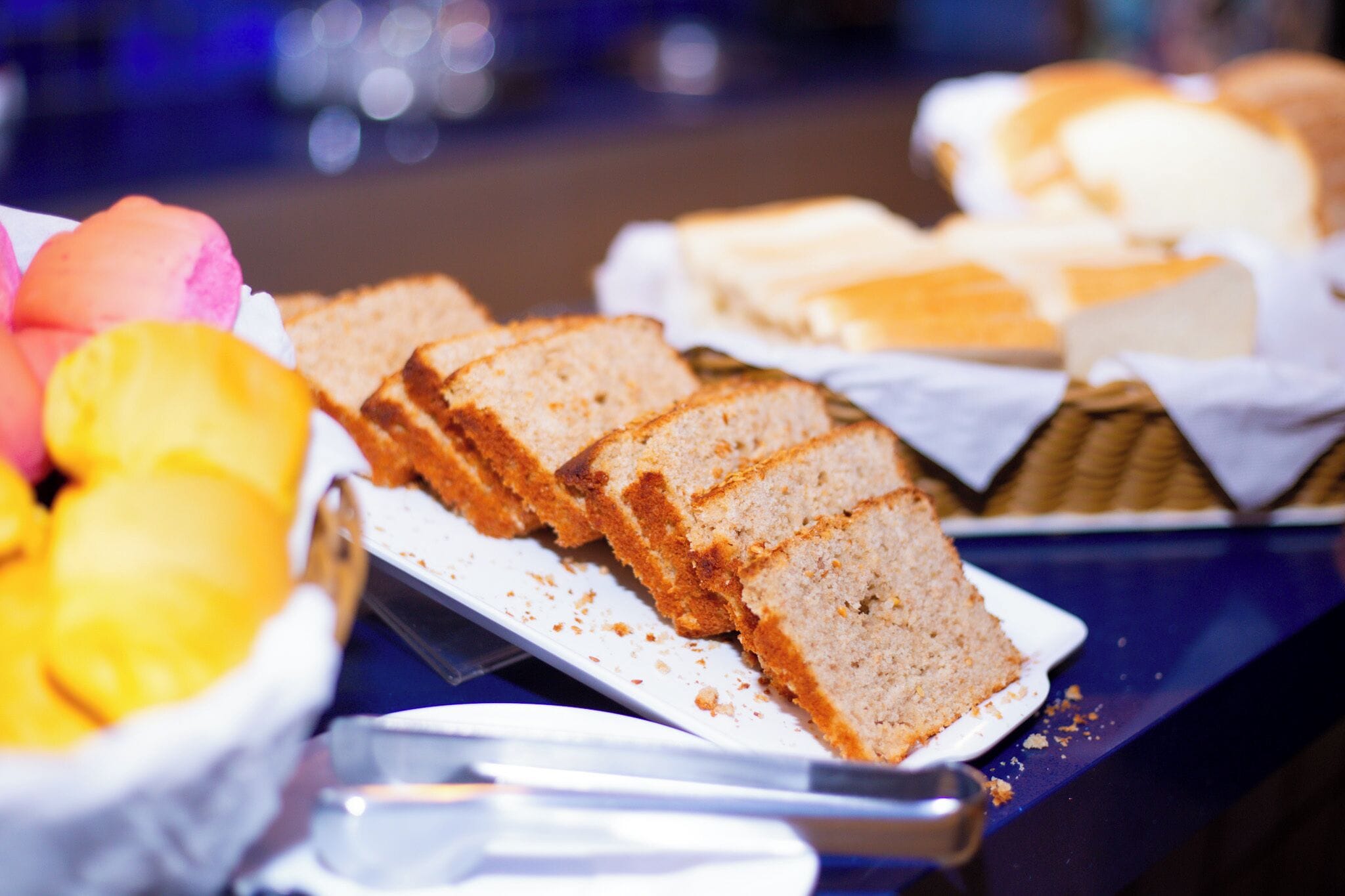 A buffet table with various food items including bread, cakes, and fruit.