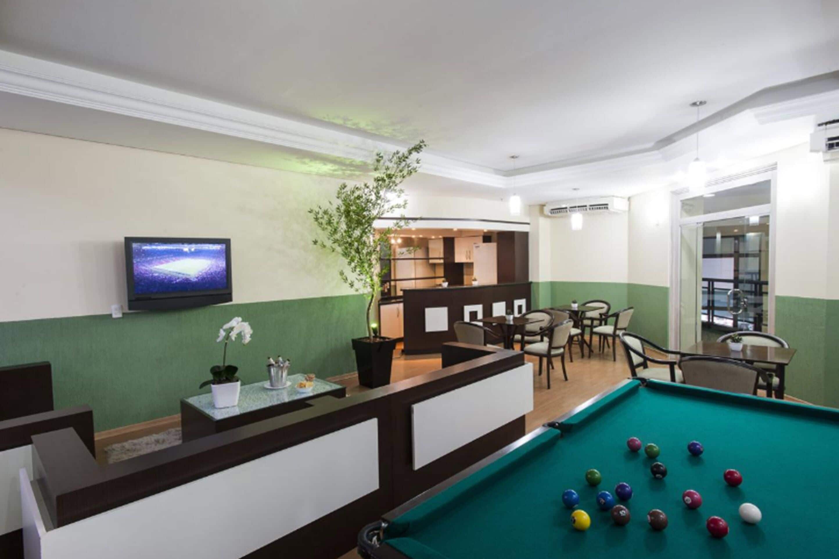 A pool table with balls, a reception desk, a television, and a seating area with chairs and tables.