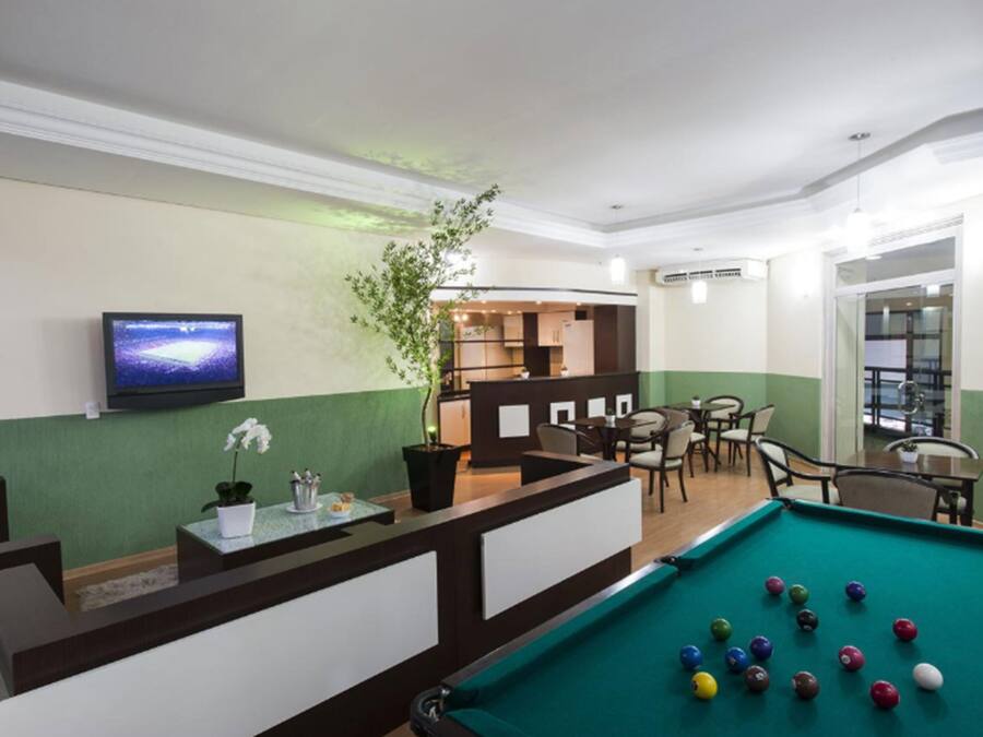 A pool table with balls, a reception desk, a television, and a seating area with chairs and tables.