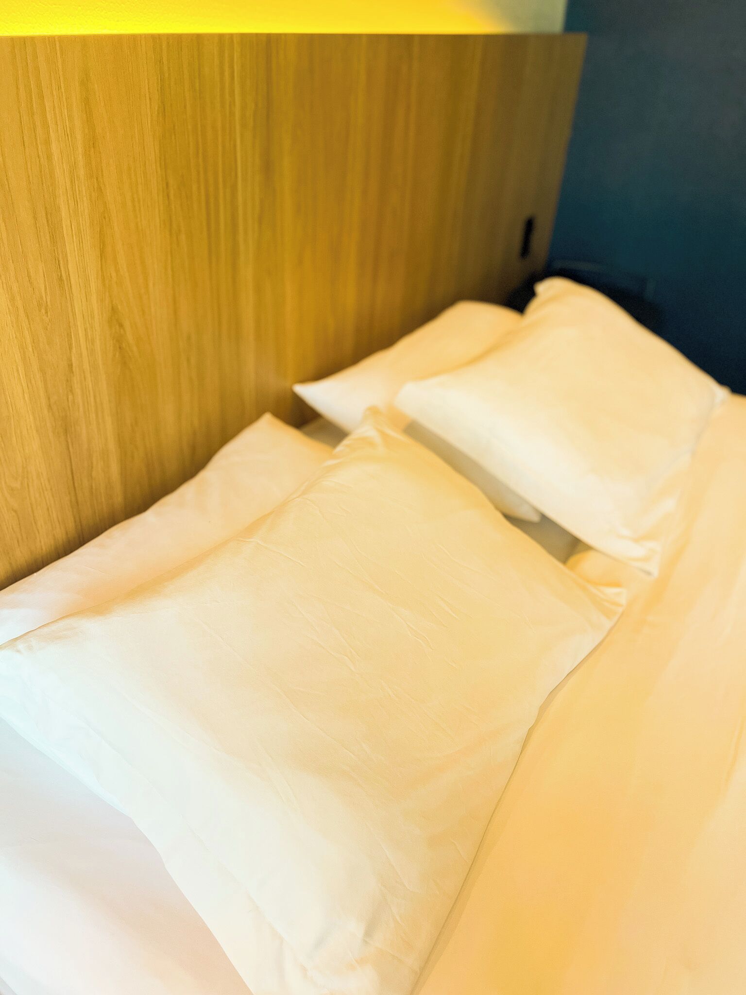 A bed with white linens and a wooden headboard.
