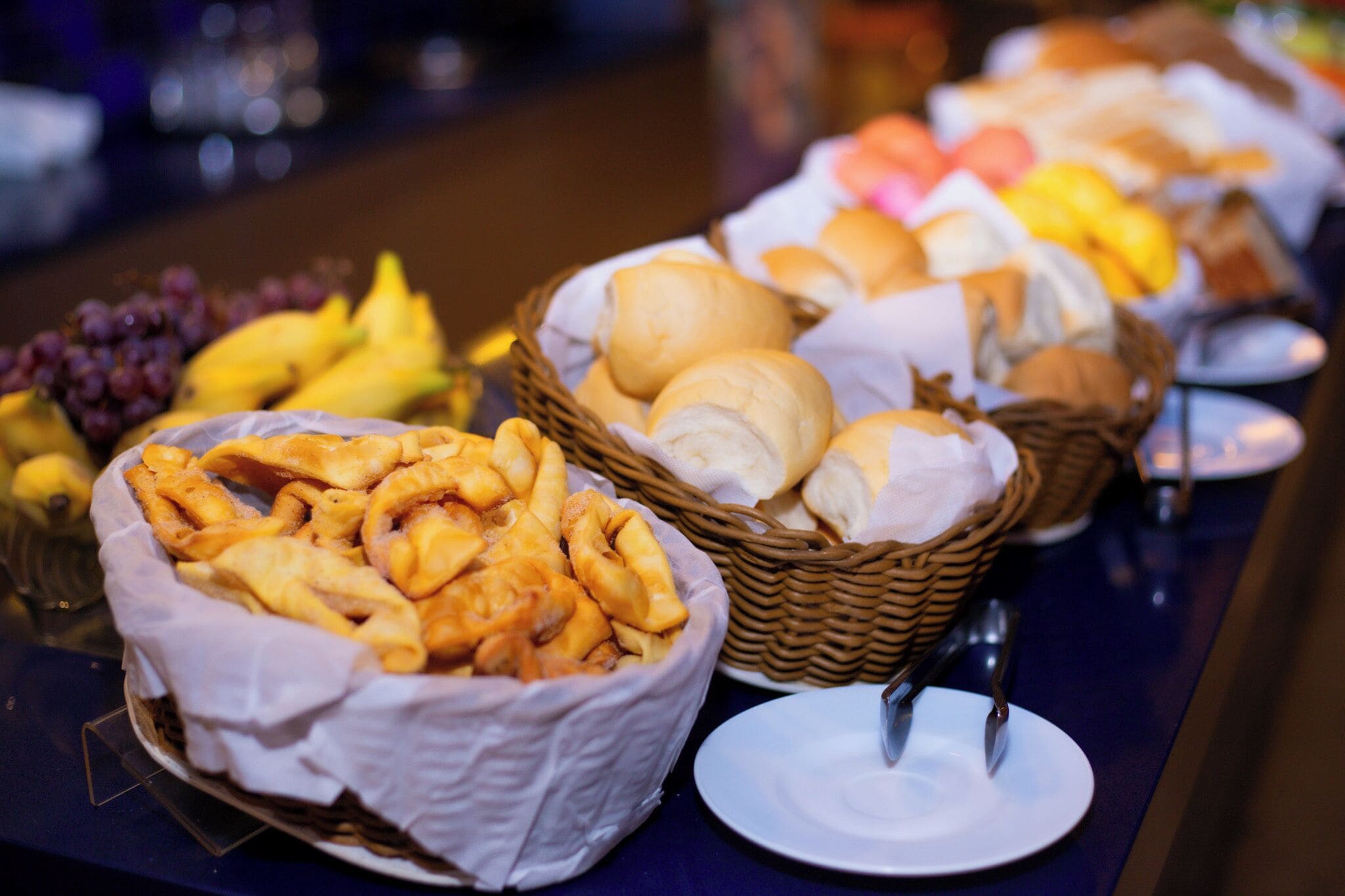 Un bufé con diversas opciones de comida, incluyendo pan, pasteles y frutas.