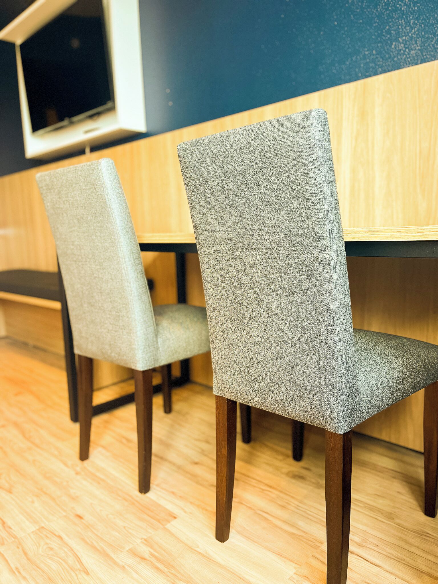 Two chairs with a textured fabric, a wooden table, and a wooden floor.