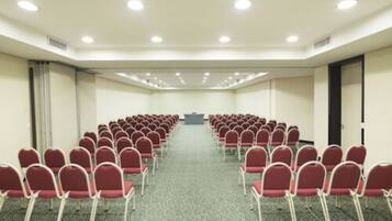 A conference room with rows of red chairs facing a podium.