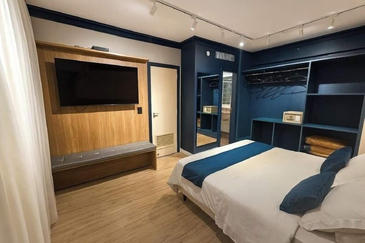 Un dormitorio moderno con una cama grande, armario empotrado y televisor montado en la pared.