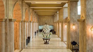 A marble-floored corridor with columns, a central floral arrangement, and seating areas. - Sheraton Kuwait, A Luxury Collection Hotel, Kuwait City (Kuwait City)