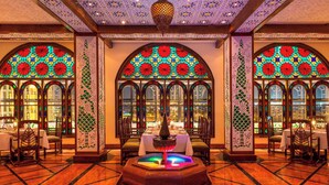 A dining area with a central fountain, arched windows with stained glass, and a patterned ceiling. - Sheraton Kuwait, A Luxury Collection Hotel, Kuwait City (Kuwait City)