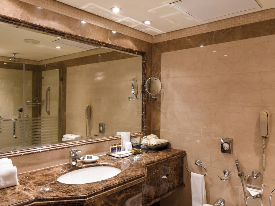Ein Badezimmer mit großem Spiegel, Waschbecken, Dusche und Toilette.