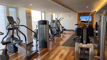 Een moderne sportschool met cardioapparaten, gewichthefmaterialen en een grote spiegel.