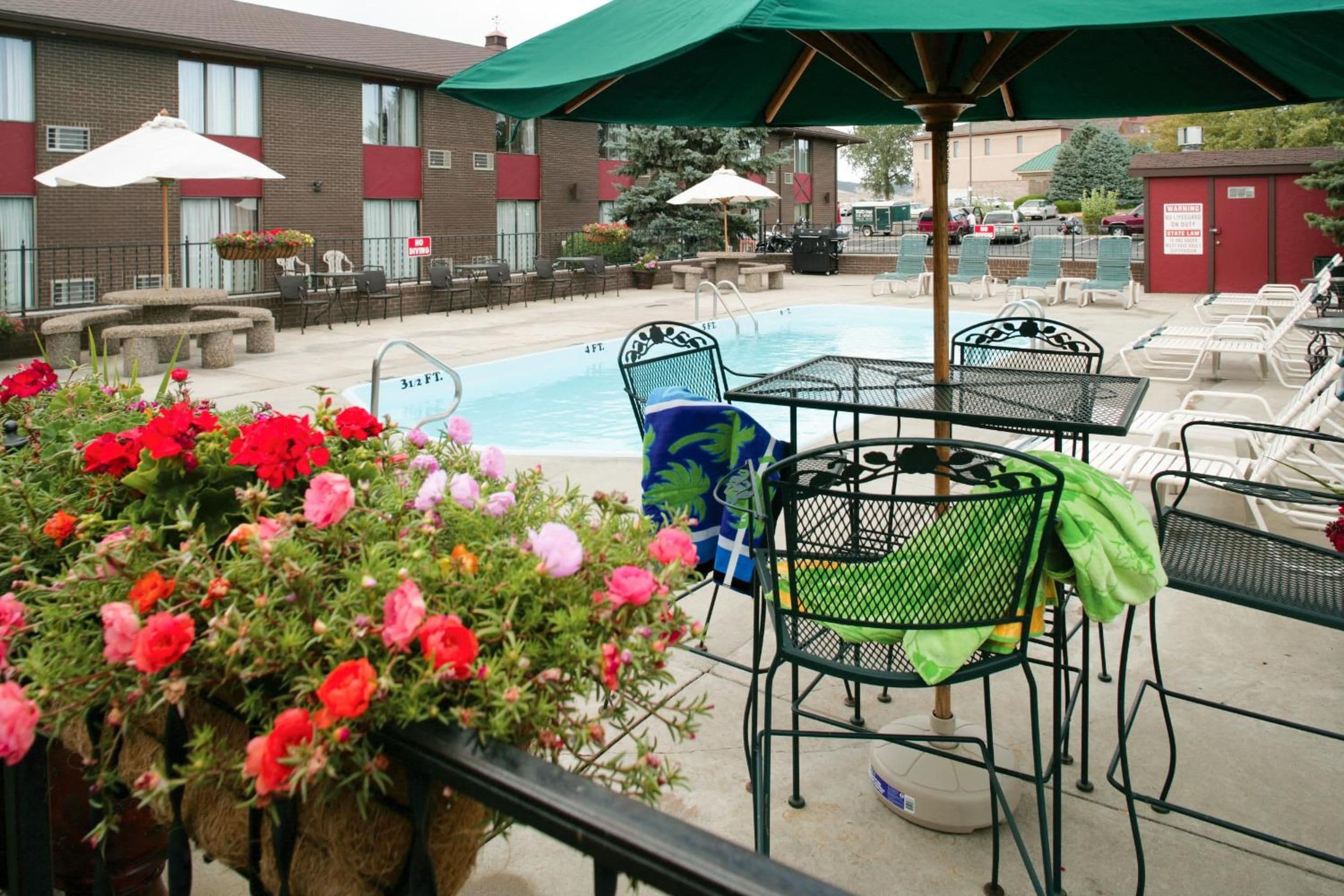 A pool area with lounge chairs, a pool table, and a flower planter.