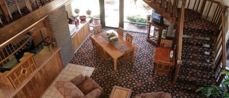 Un salón espacioso con escalera de madera, una mesa de comedor y suelo estampado.
