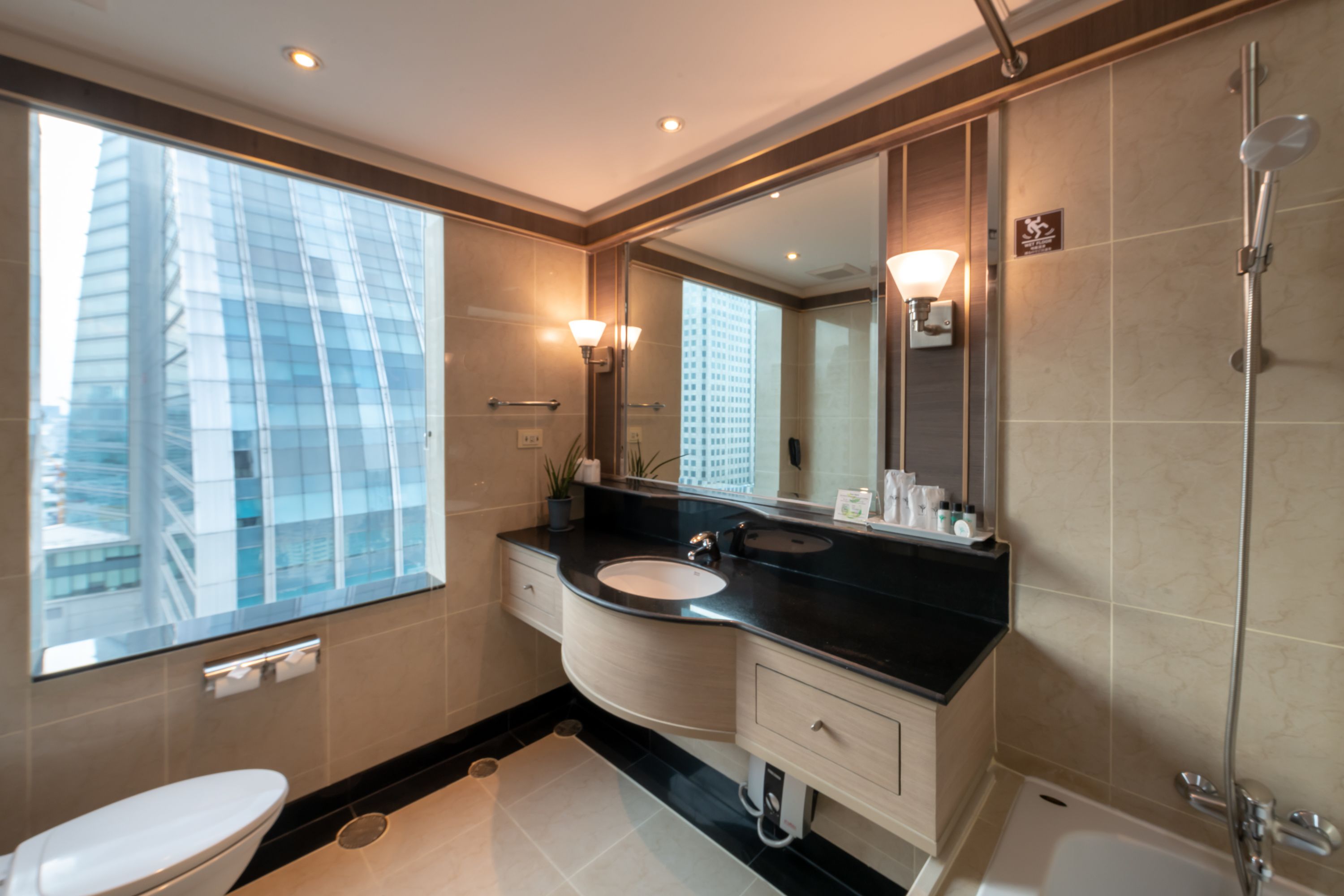 A modern bathroom with a large mirror, two sinks, a toilet, and a shower.