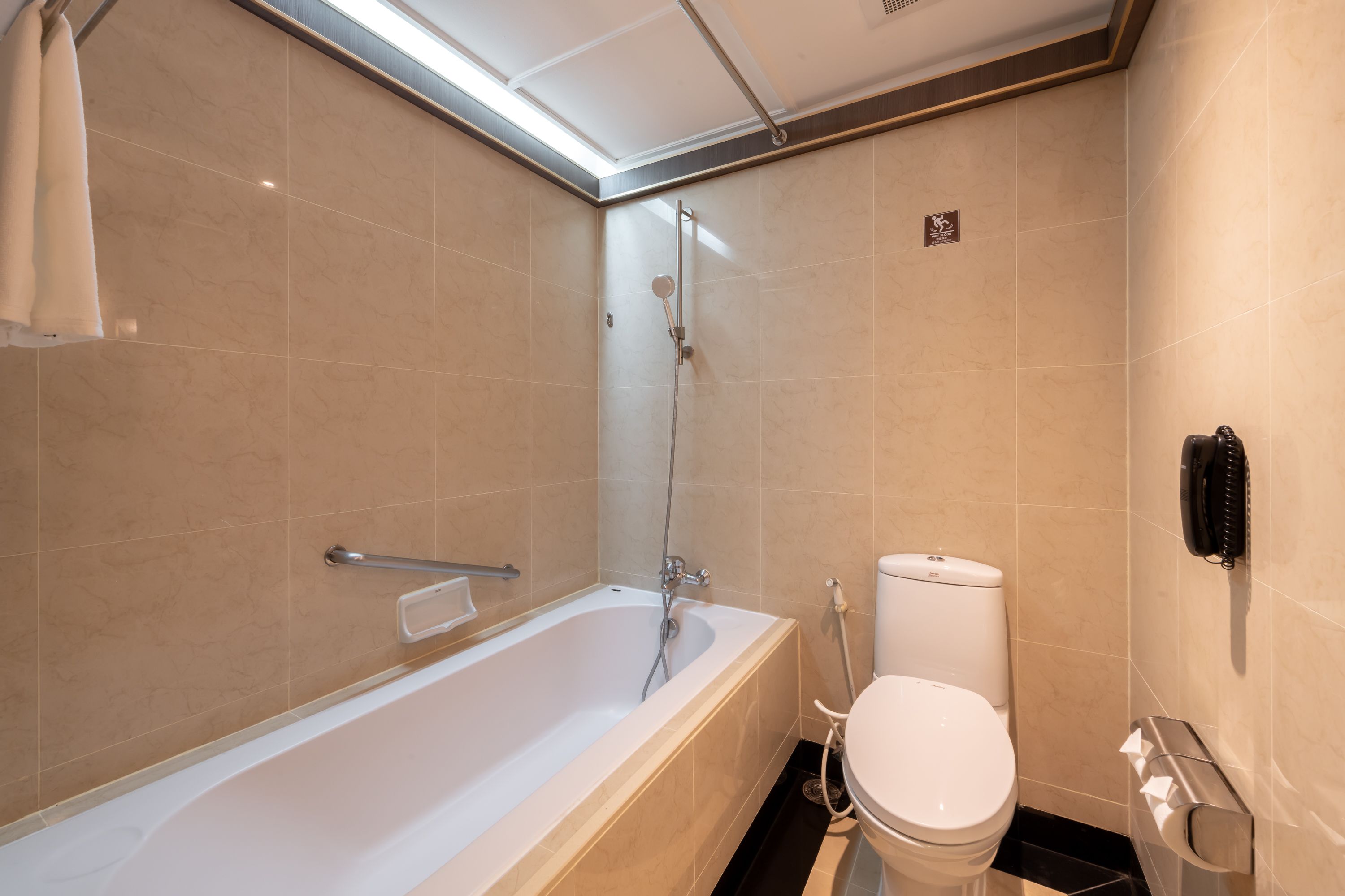 A modern bathroom with a bathtub, toilet, and a towel rack.