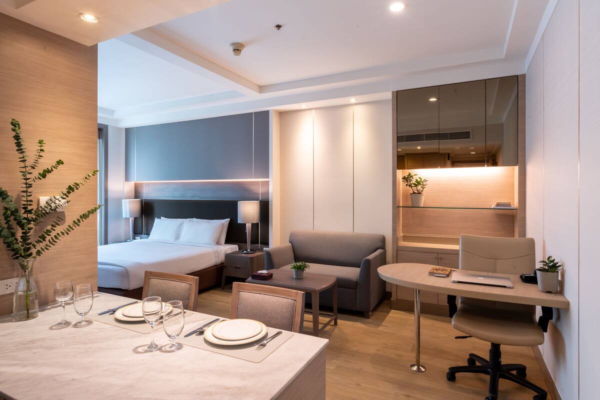 Una habitación de hotel moderna con cama, sofá, escritorio y zona de comedor.