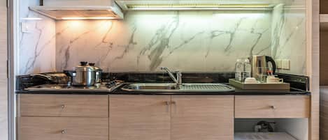 A compact kitchen with wooden cabinets, a stainless steel sink, a microwave, and a coffee maker.