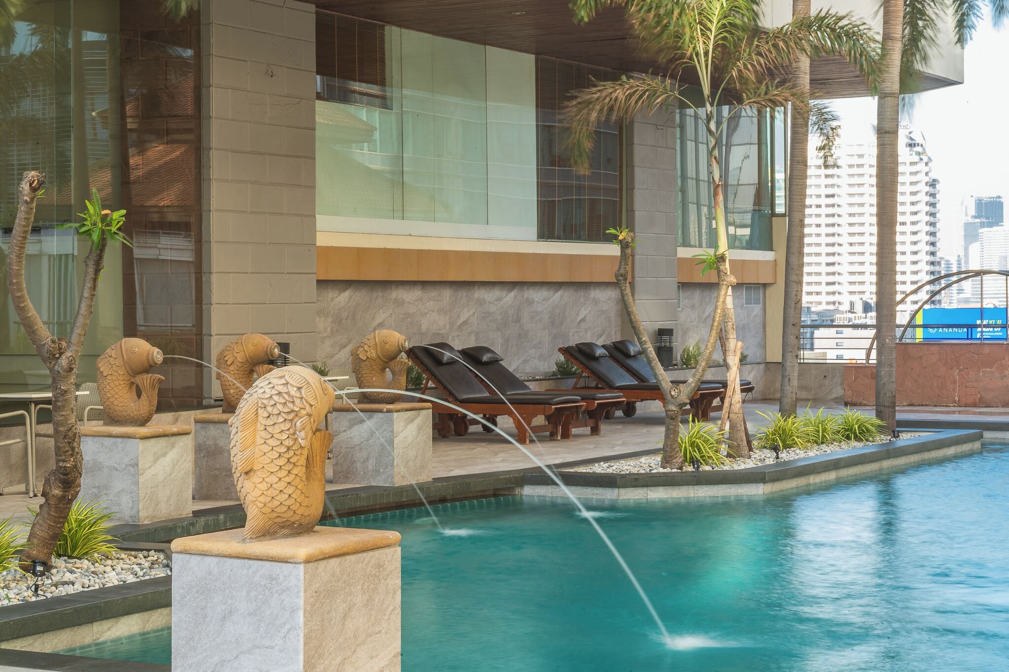 A modern pool area with lounge chairs and decorative fish sculptures.