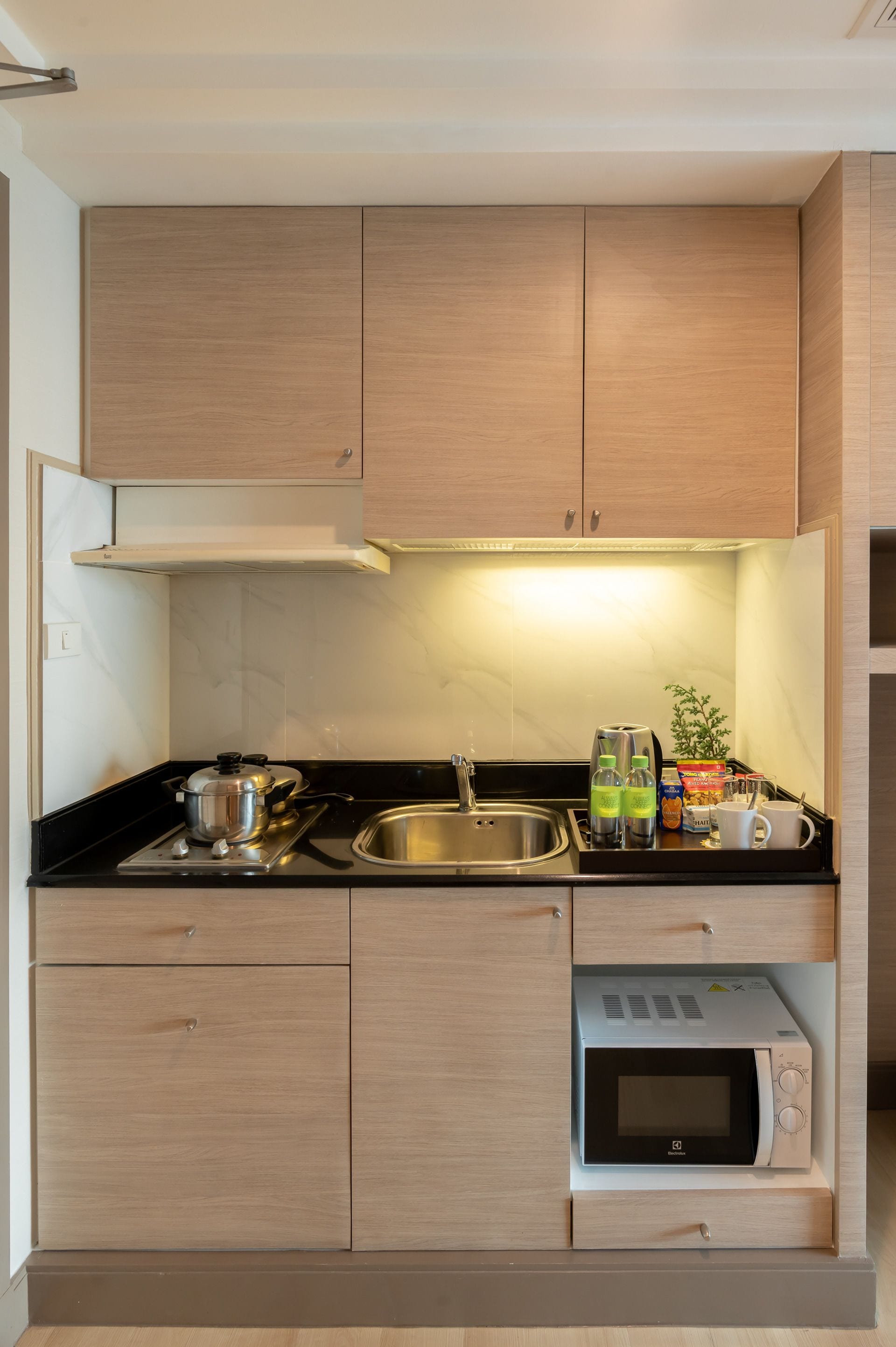 A compact kitchen with wooden cabinets, a built-in microwave, a stove, and a sink.