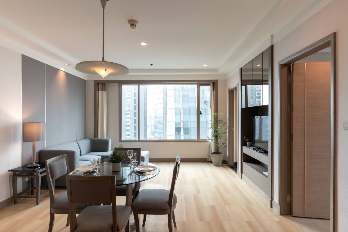 Un salón moderno con mesa de comedor, sofá y ventanas amplias que ofrecen vistas de la ciudad.
