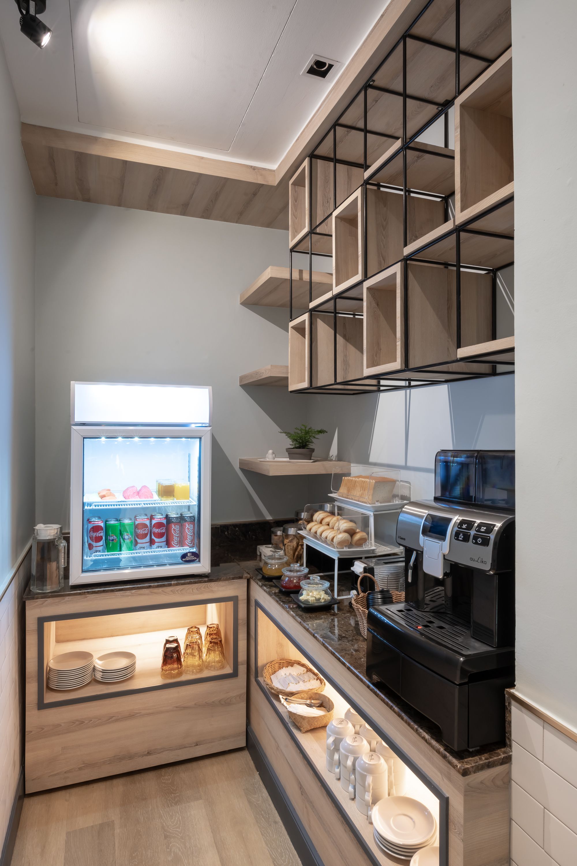 Un espacio de cocina compacto con refrigerador, cafetera y estantes para almacenamiento.