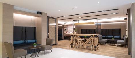 A modern, well-lit room with a seating area, a dining table, and a bookshelf.