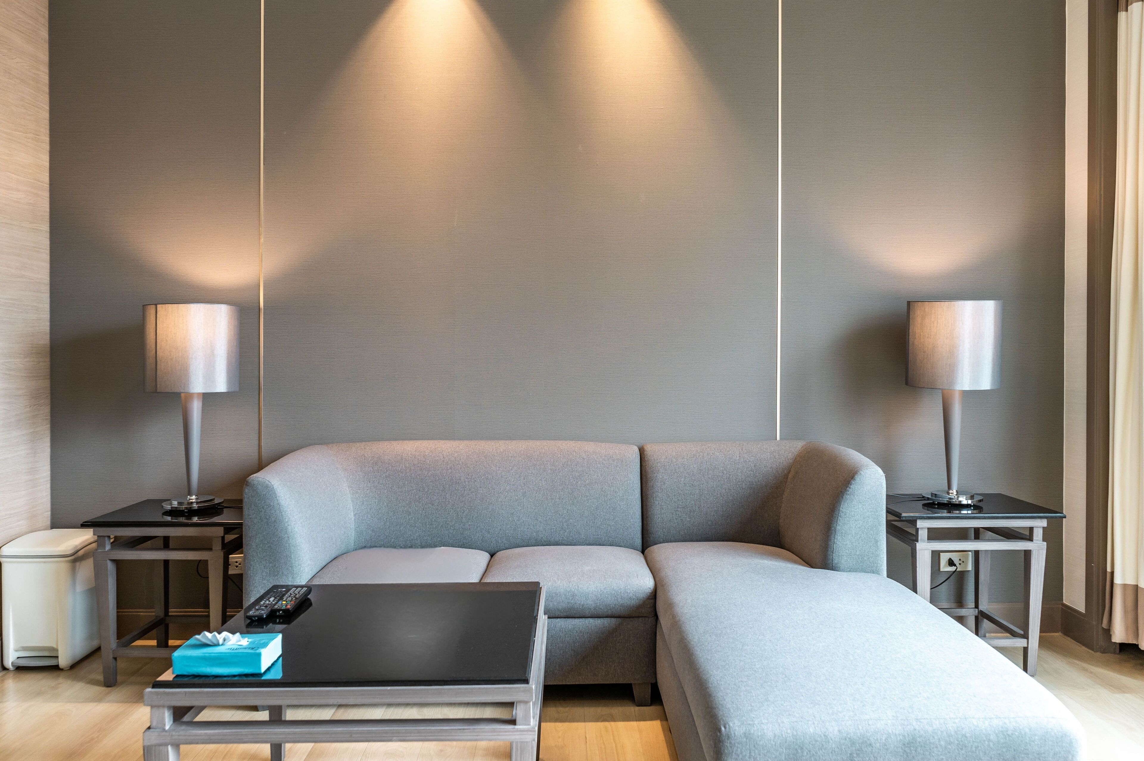 A modern living room with a grey sectional sofa, a black coffee table, and two side tables with lamps.